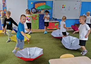 Dzieci biorą udział w zabawie z parasolami